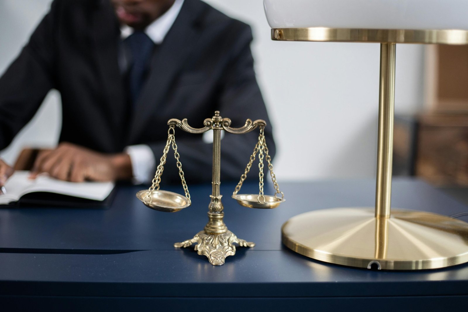 Elegant legal office with a close-up of golden scales of justice on a sleek dark desk.